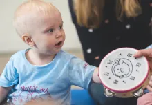 a young child at a Monkey Music class playing a tambourine